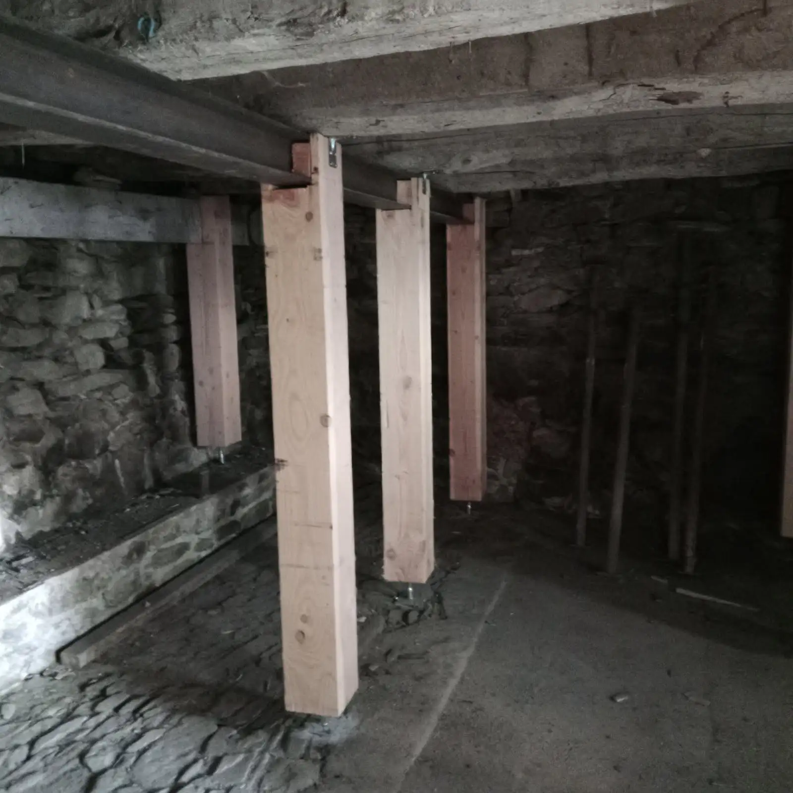 Après : cave renforcée avec plusieurs poteaux en bois soutenant les poutres du plafond